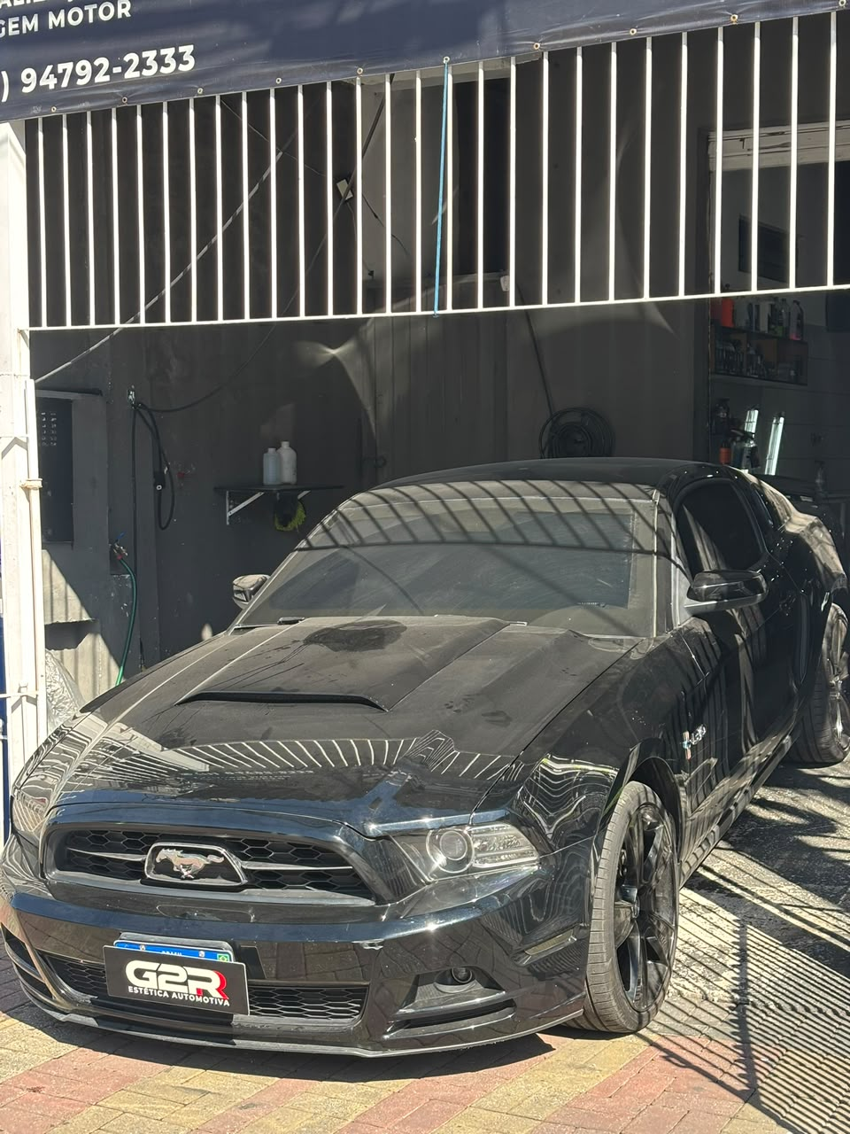Mustang antes do atendimento, com poeira sobre o capô